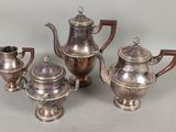 trois théières en argent et une cafetière sur une table