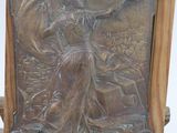 a bronze plaque of a woman on a chair