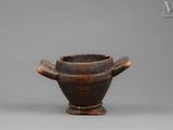 an old wooden bowl with a handle on a gray surface