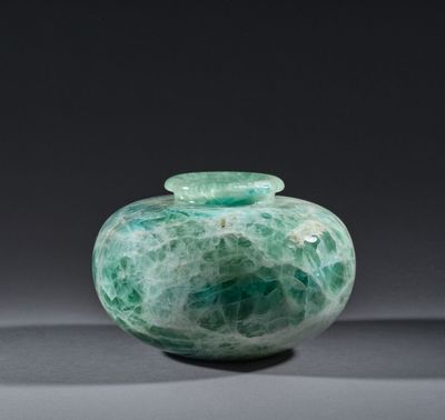 une photo d'un vase en verre vert sur fond noir