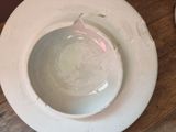 a white bowl sitting on a wooden table next to a plate