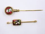 two gold tone hair pins with red and green designs on them