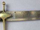 a sword with a gold handle on a white surface
