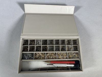 a metal box filled with assorted metal items on a white surface