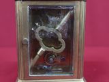 a silver clock with a key on it on a red surface