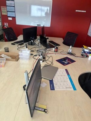 Plusieurs ordinateurs portables sont posés sur une table dans un bureau.