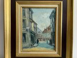 une peinture à l'huile représentant une scène de rue, dans un cadre doré, posée sur une surface en marbre