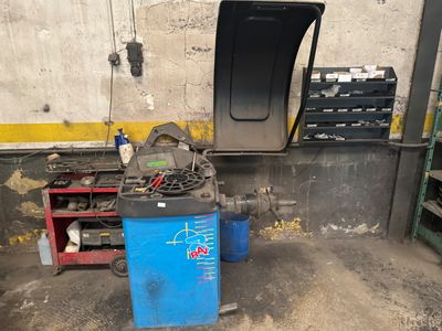 une photo d'un garage avec une poubelle bleue et des outils