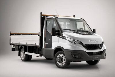 La petite camionnette blanche est garée sur une surface grise.