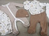 several baby clothes and a hat are laid out on the floor