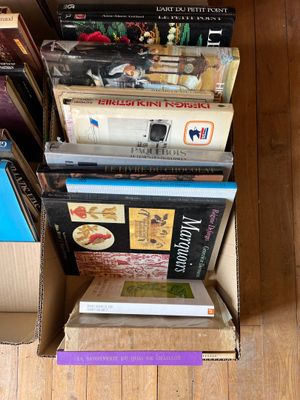de nombreux livres empilés les uns sur les autres dans une boîte en carton
