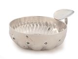 a silver bowl with a spoon in it on a white surface