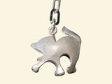 silver cat charm on a chain on a white background