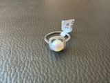a white oplite ring with a ribbon around it sitting on a leather surface
