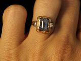 a woman ' s hand holding a ring with a blue stone