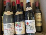 Plusieurs bouteilles de vin sont posées dans une boîte en carton sur une étagère
