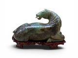 statue d'un cheval couché sur un morceau de bois posé sur une surface blanche