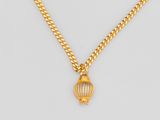 un collier en or avec un pendentif en forme de cage à oiseaux, monté sur une chaîne
