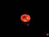 a close up of a red stone on a black surface