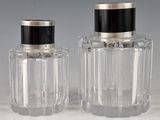 pair of clear glass bottles with black lids on a white surface