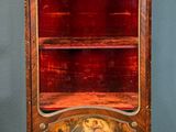 an old wooden cabinet with a red glass door and gold trimming