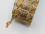 a close up of a gold bracelet on a white surface