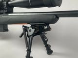 a close up of a rifle with a scope on a tripod