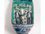 a blue and white ceramic plaque with a crucifix on it