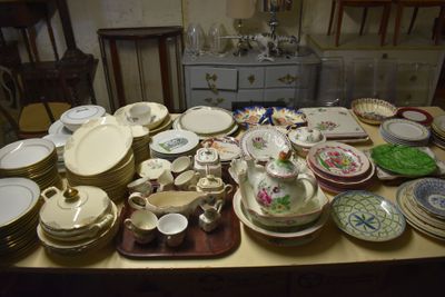 de nombreuses assiettes et bols posés sur une table, avec une commode en arrière-plan