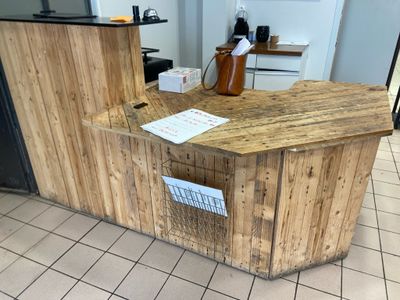 a wooden counter in the middle of a tiled floor