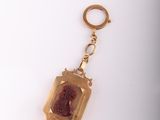 an image of a gold keychain with a red stone in it