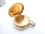 a gold pocket watch sitting on a white surface