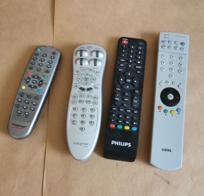 quatre télécommandes sont alignées sur une surface marron