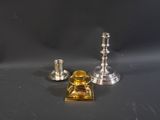 deux bougeoirs en argent et un bougeoir en verre posés sur une table