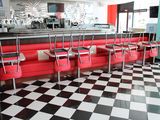 sol à carreaux noirs et blancs dans un snack-bar avec des banquettes rouges