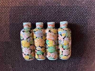 quatre petites bouteilles ornées de motifs différents, posées sur une chaise