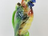 a figurine of a parrot sitting on a green plant