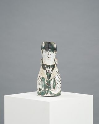 figurine en céramique représentant un chien sur un socle, sur fond gris
