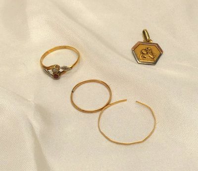 trois bagues en or et une bague sertie d'un diamant, posées sur un tissu blanc