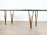 La table est fabriquée à partir de branches et possède un plateau noir.