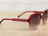 the sunglasses are red and brown on a wooden table