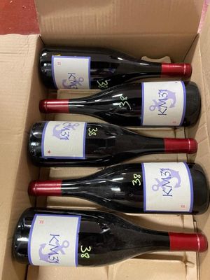 six bottles of red wine in a cardboard box on a table
