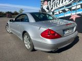 une Mercedes SLK argentée garée devant un immeuble dont le mur est recouvert de graffitis