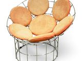 a metal chair that has a bunch of pillows on it