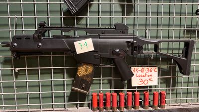 une arme exposée dans une vitrine, avec une étiquette indiquant son prix