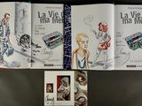 three books with illustrations of people and a camera on a table