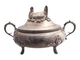 an antique silver plate with two handles and a dog head on the top