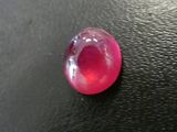 a red stone with a hole in it on a black surface
