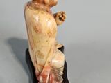 figurine of a boy sitting on a rock with a flower in his hand