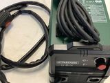 a green and black power supply sitting on a white table